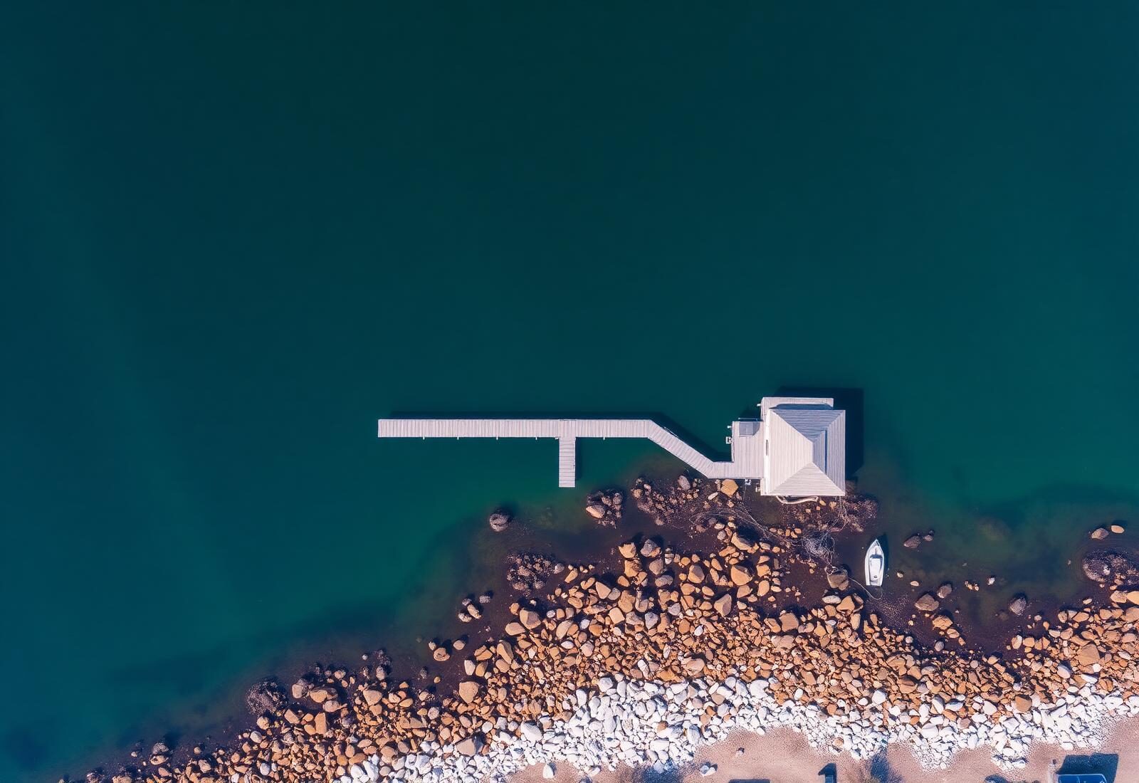 Aerial view of a residential waterfront property with a private pier and boathouse